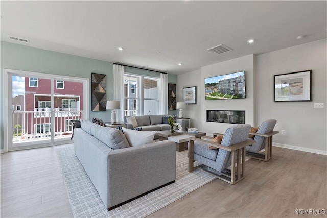 living area with light wood-type flooring, baseboards, and recessed lighting