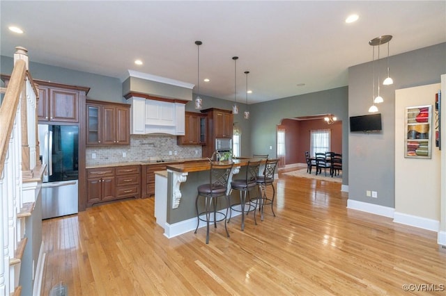 405 Church St, Blackstone, VA 23824 - kitchen with a breakfast bar, smart refrigerator, light wood-style flooring, backsplash, and arched walkways