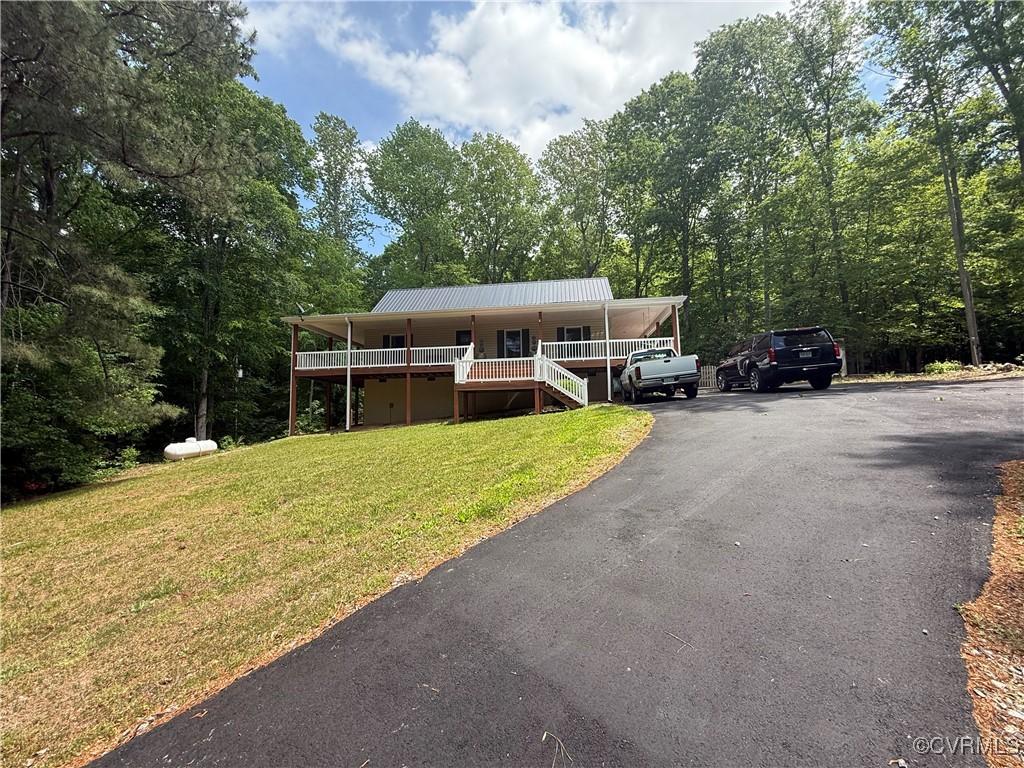 view of front of property with metal roof, a porch, driveway, and a front yard