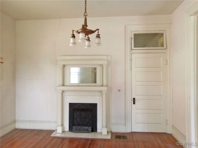 unfurnished living room with a fireplace with flush hearth, a notable chandelier, baseboards, and wood finished floors