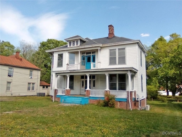back of property featuring a porch, a chimney, a lawn, and a balcony