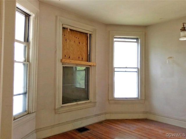 unfurnished room featuring a wealth of natural light, visible vents, and wood finished floors