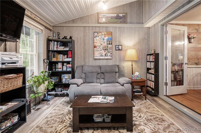 living area with wooden walls, lofted ceiling, and wood finished floors