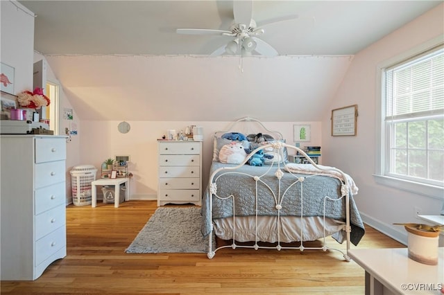 bedroom featuring vaulted ceiling, light wood-type flooring, baseboards, and a ceiling fan