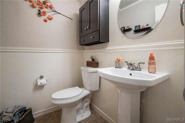 bathroom featuring toilet, tile patterned flooring, wainscoting, and baseboards