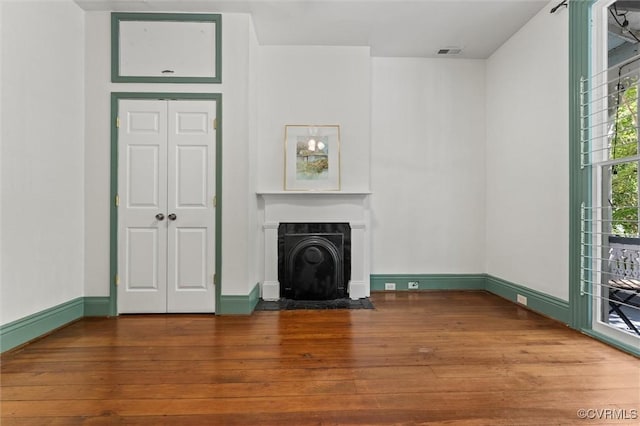 unfurnished living room with hardwood / wood-style flooring, a fireplace with flush hearth, and baseboards