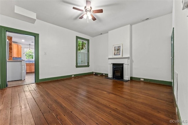 unfurnished living room with wood-type flooring, a ceiling fan, a fireplace, and baseboards