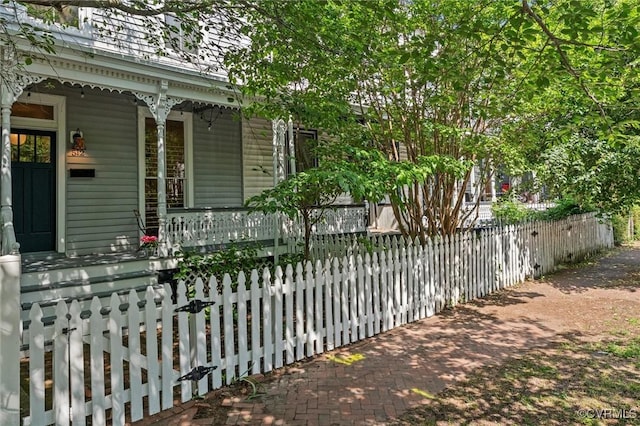 view of property exterior featuring a porch and a fenced front yard