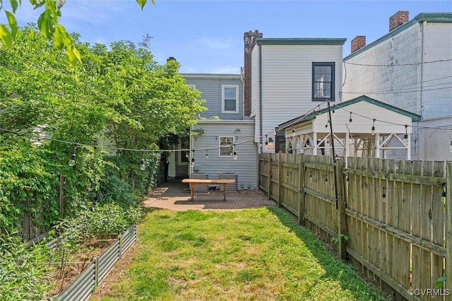 back of property featuring a patio area and a vegetable garden