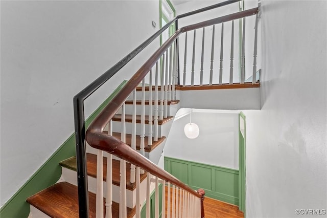staircase featuring wood finished floors and wainscoting