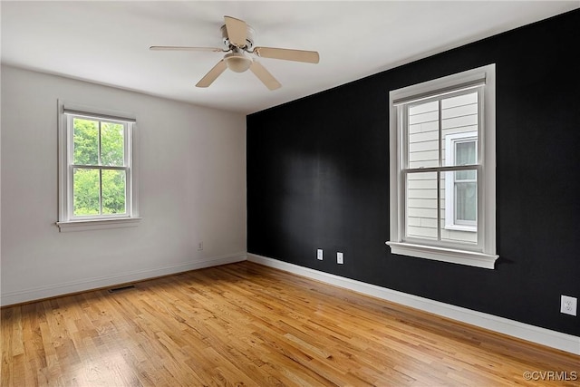 spare room featuring light wood-style floors, baseboards, and ceiling fan