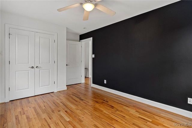 unfurnished bedroom with light wood finished floors, baseboards, a closet, and a ceiling fan