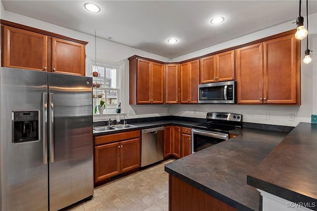 kitchen with stainless steel appliances, dark countertops, a sink, recessed lighting, and brown cabinets