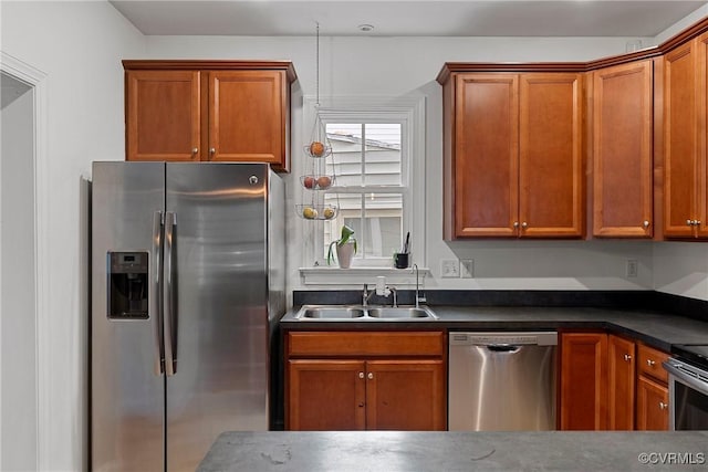 kitchen with stainless steel appliances, a sink, dark countertops, and brown cabinets