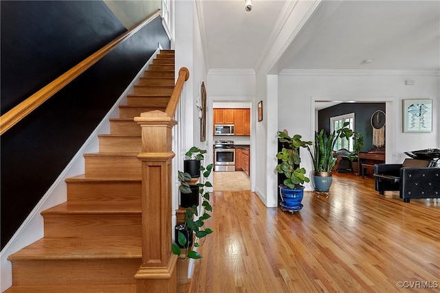 stairway featuring wood finished floors and ornamental molding