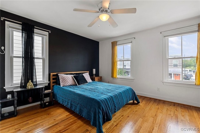 bedroom with light wood-type flooring, baseboards, and a ceiling fan