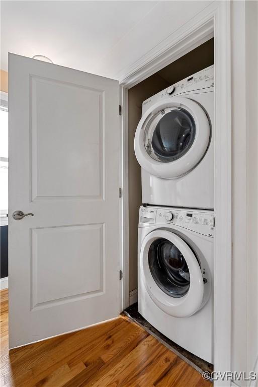 laundry room with estacked washer and dryer and wood finished floors