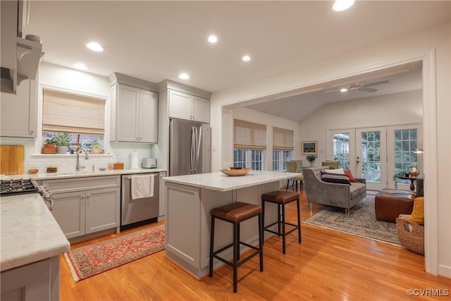 kitchen featuring appliances with stainless steel finishes, open floor plan, a breakfast bar, backsplash, and plenty of natural light