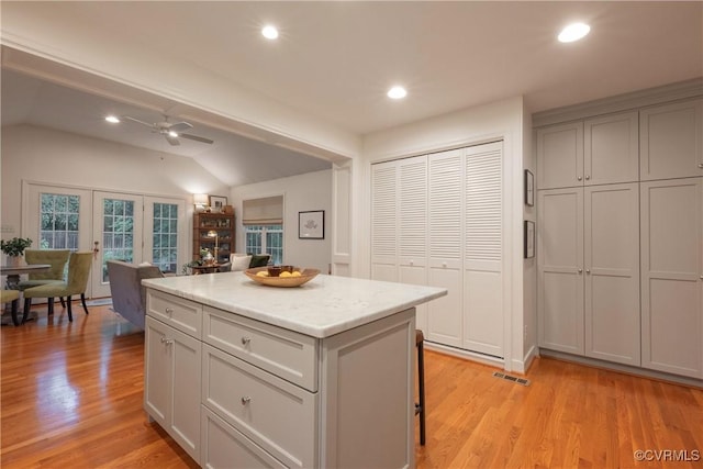 kitchen with a center island, a ceiling fan, light wood-type flooring, a breakfast bar area, and lofted ceiling