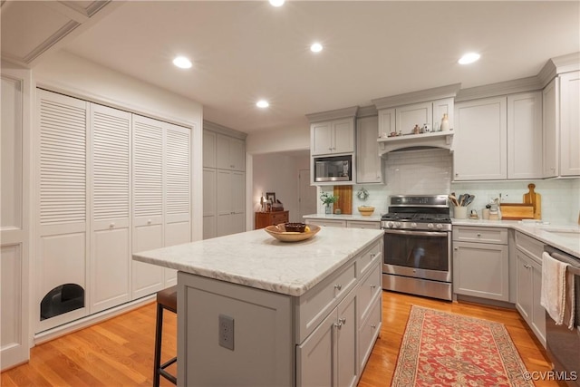 kitchen featuring stainless steel appliances, gray cabinets, a kitchen island, decorative backsplash, and recessed lighting