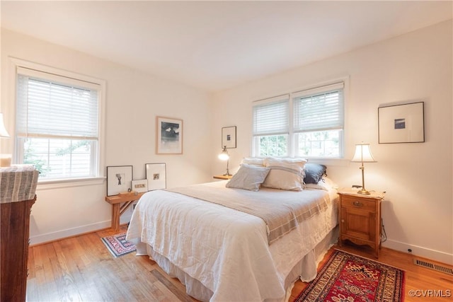 bedroom featuring multiple windows, light wood-style flooring, and baseboards