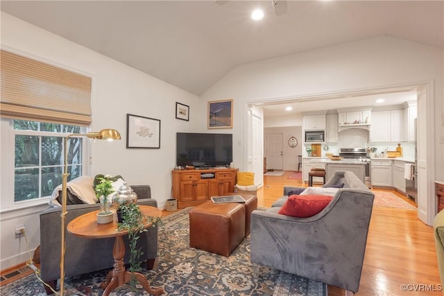 living room featuring lofted ceiling, light wood-style floors, and recessed lighting