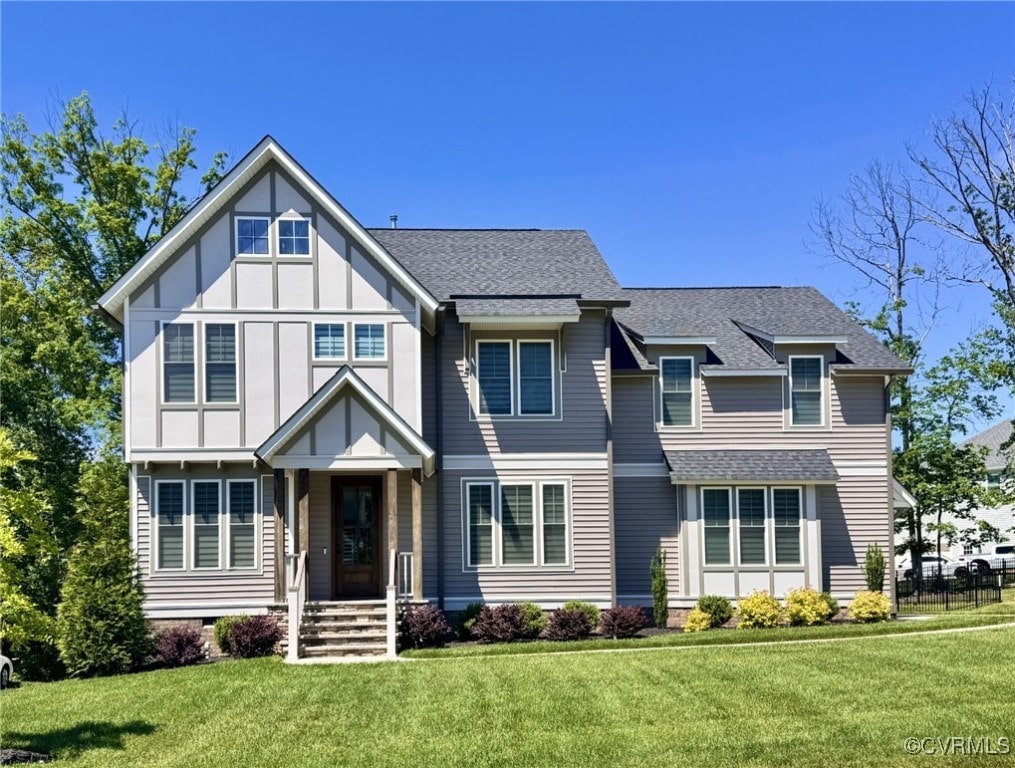 view of front of property with a front lawn, a shingled roof, and board and batten siding
