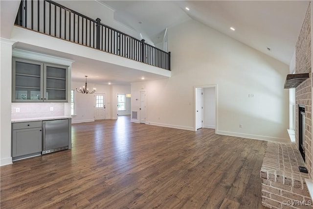 15148 Johns Trace Cir, Montpelier, VA 23192 - unfurnished living room with a brick fireplace, a chandelier, dark wood finished floors, high vaulted ceiling, and baseboards