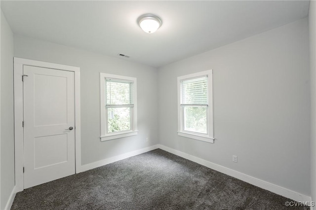empty room with dark carpet and baseboards