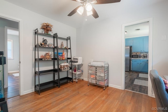 office area featuring light wood finished floors, a ceiling fan, and baseboards