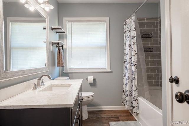 bathroom featuring baseboards, wood finished floors, toilet, vanity, and shower / bath combo