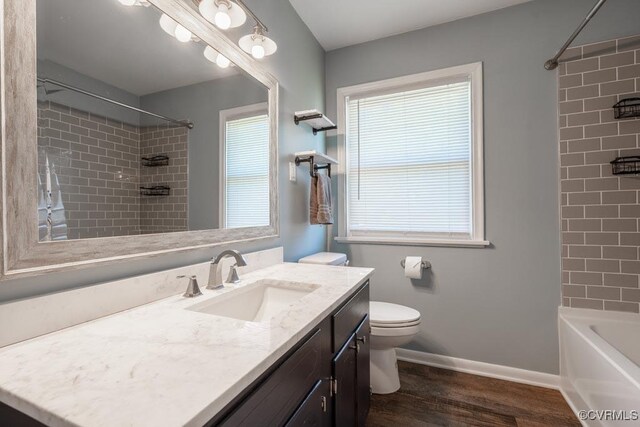 bathroom with wood finished floors, toilet, vanity, baseboards, and shower / bathtub combination