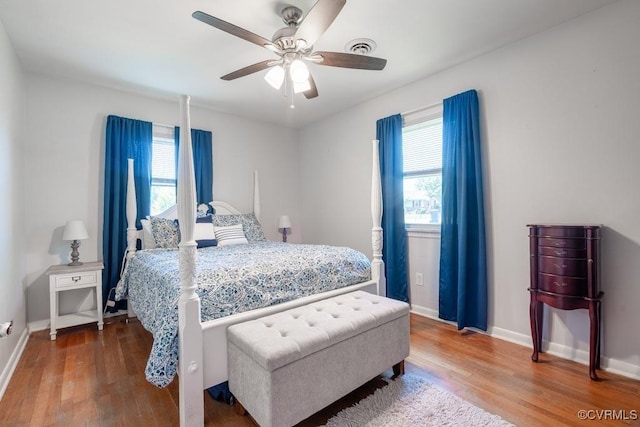 bedroom with wood finished floors, multiple windows, and baseboards