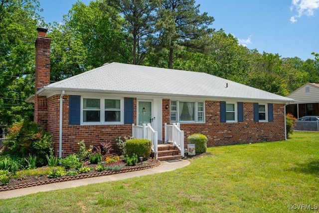 ranch-style house with a chimney, brick siding, and a front yard