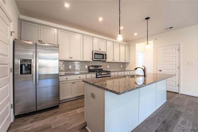 kitchen featuring stainless steel appliances, a sink, dark wood-style flooring, backsplash, and stone counters
