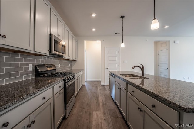 kitchen featuring appliances with stainless steel finishes, a sink, tasteful backsplash, gray cabinetry, and recessed lighting