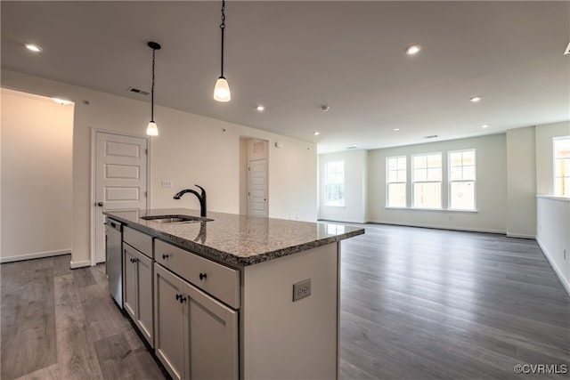 kitchen with a sink, an island with sink, dark stone countertops, dark wood-style flooring, and dishwasher