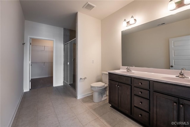 full bathroom featuring toilet, a shower stall, tile patterned flooring, double vanity, and a walk in closet