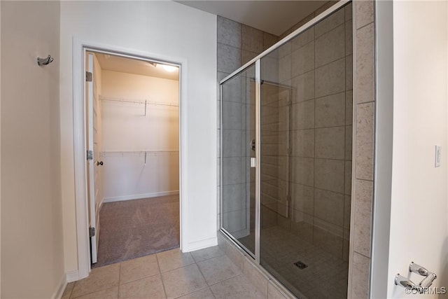 full bathroom with a shower stall, tile patterned floors, a walk in closet, and baseboards