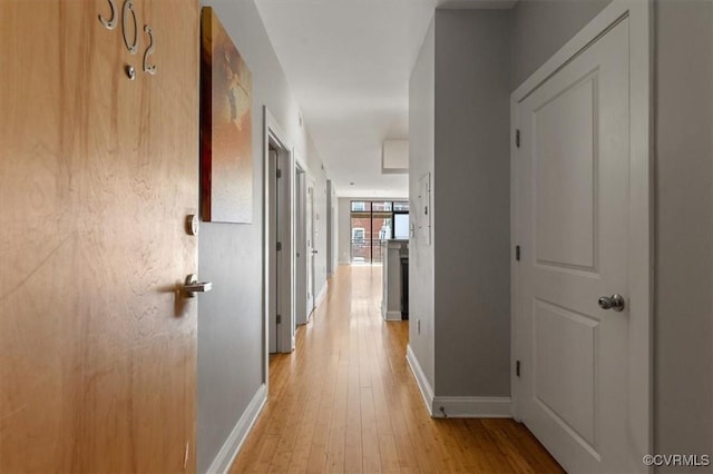 corridor with baseboards and light wood-type flooring