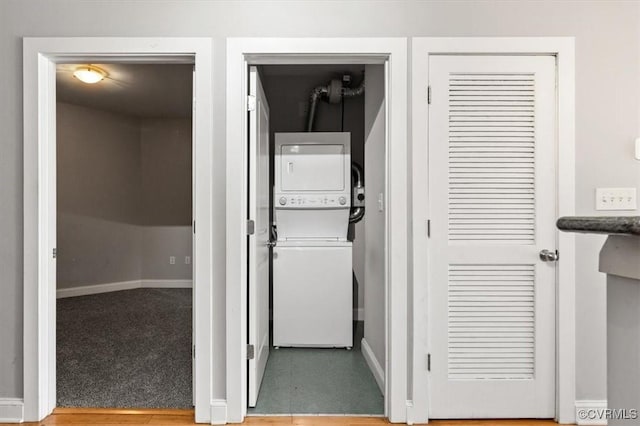 laundry room with stacked washer and clothes dryer and baseboards