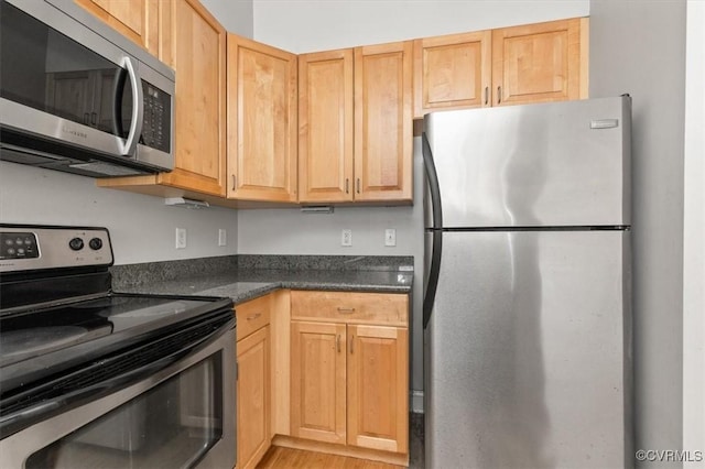 kitchen with appliances with stainless steel finishes, dark countertops, and light brown cabinets