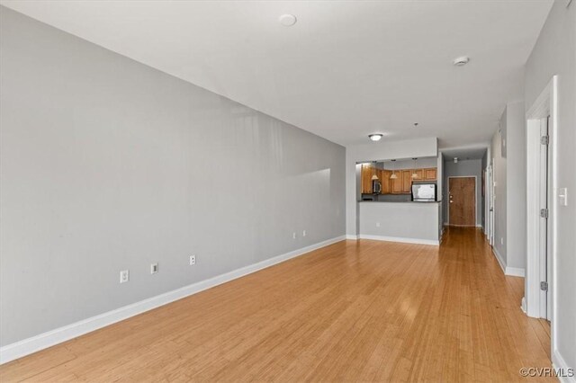 unfurnished living room with light wood-style flooring and baseboards