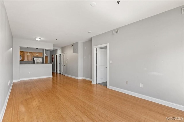 unfurnished living room with light wood-style flooring and baseboards