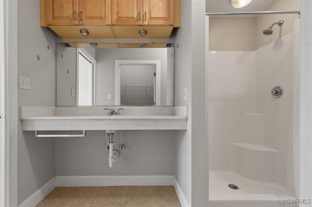 bathroom with a stall shower, baseboards, and tile patterned flooring