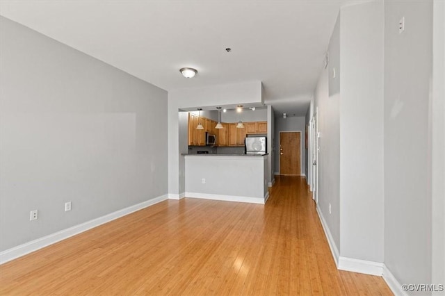 unfurnished living room featuring light wood finished floors, baseboards, and track lighting
