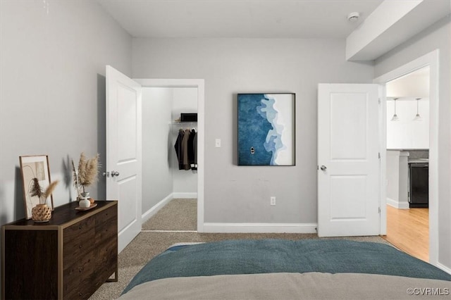 bedroom with a spacious closet, carpet floors, baseboards, and a closet