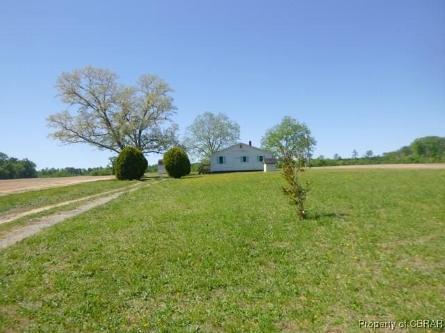 view of grassy yard with a view of countryside and driveway