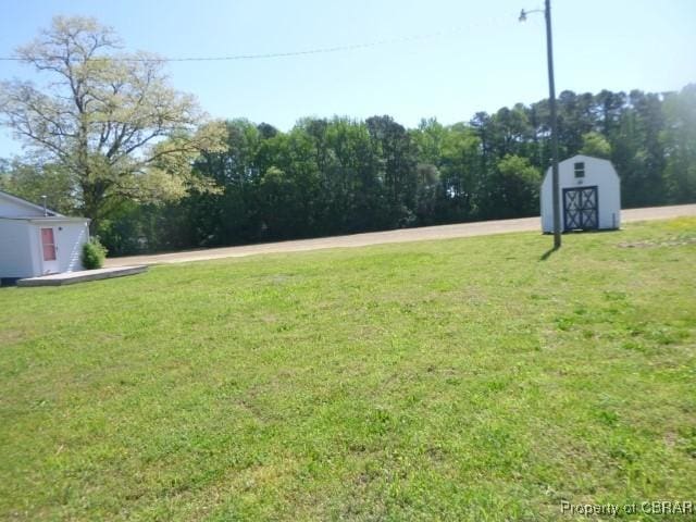 view of green lawn featuring a storage shed and an outdoor structure