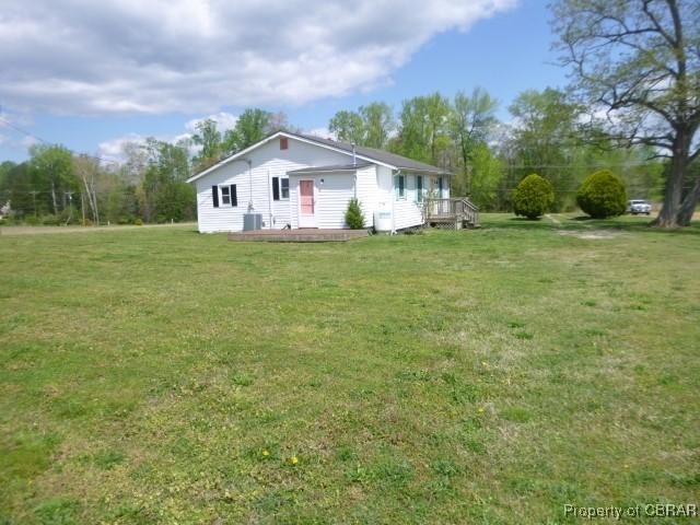 view of front of property with a front yard, a wooden deck, and central AC unit